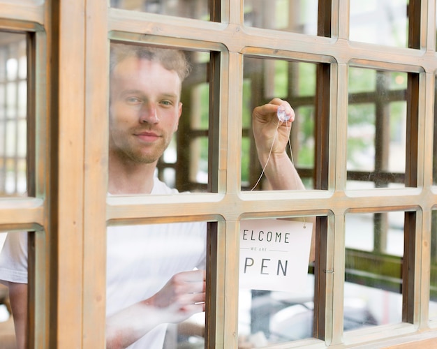 Hombre poniendo señal abierta en la ventana de la cafetería