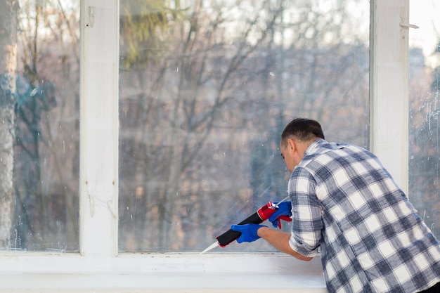 Hombre poniendo silicona en una pared.