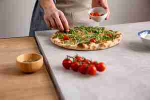 Foto gratuita hombre poniendo tomates en masa de pizza al horno con rodajas de salmón ahumado