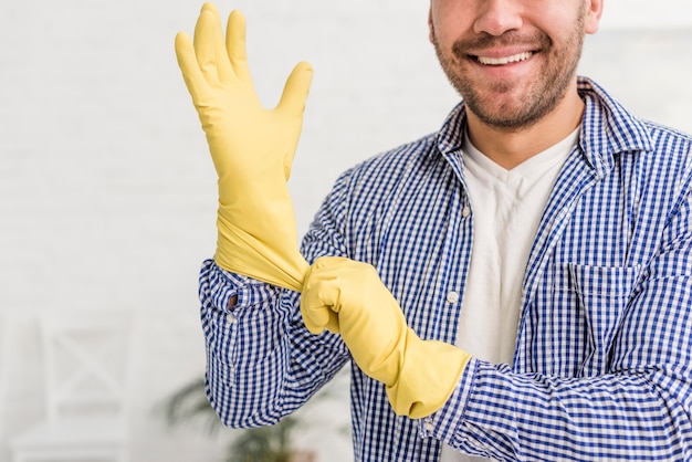 Hombre poniéndose guantes de goma para limpiar la casa
