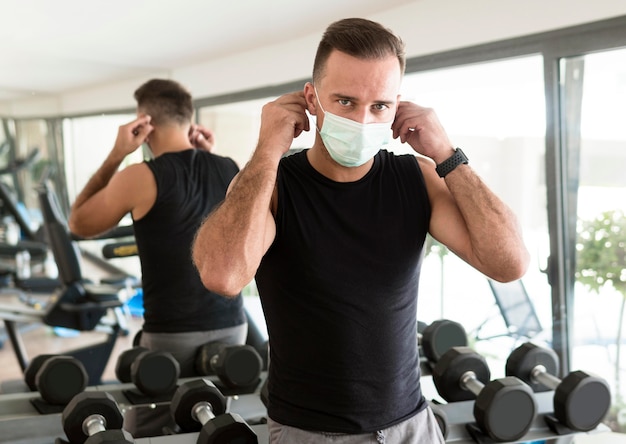 Hombre poniéndose máscara médica en el gimnasio