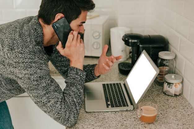 Hombre con portátil hablando por teléfono