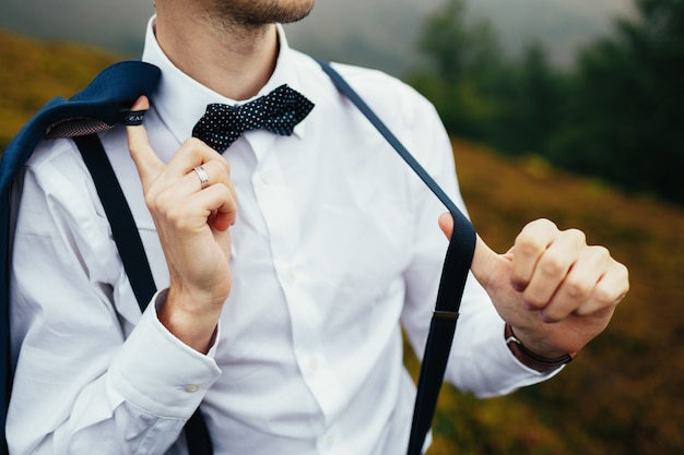 Hombre posa en camisa blanca con tirantes