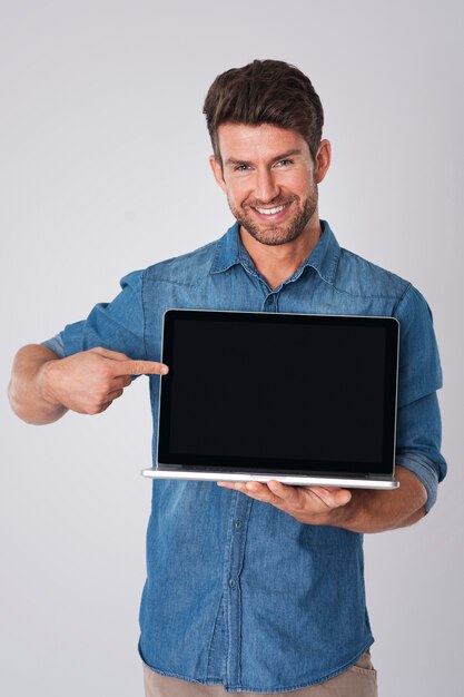 hombre posando con camisa vaquera y portátil