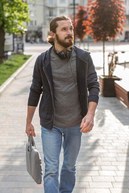 Hombre posando en la ciudad mientras usa auriculares