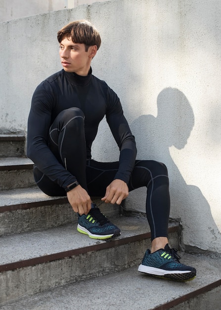 Hombre posando en las escaleras mientras usa ropa deportiva