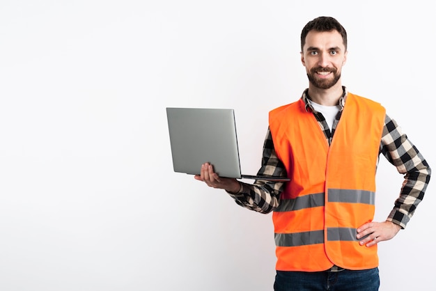 Hombre posando con laptop y chaleco de seguridad