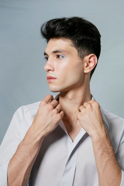 Hombre posando mientras sostiene el cuello de la camisa