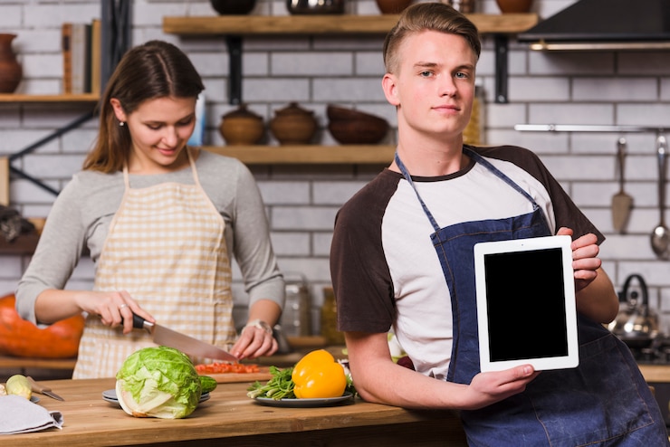 Foto gratuito hombre posando con tableta mientras mujer cocinando