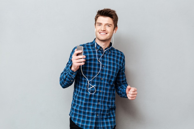 Hombre positivo bailando mientras escucha música en el teléfono inteligente