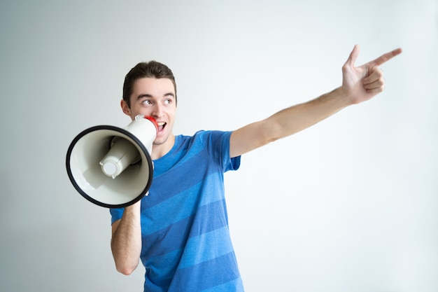 Hombre positivo hablando en megáfono y apuntando a un lado