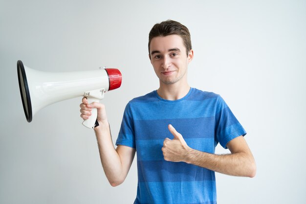 Hombre positivo sosteniendo el megáfono y mostrando el pulgar hacia arriba