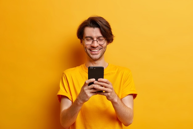 Hombre positivo usa un teléfono celular moderno para chatear en línea