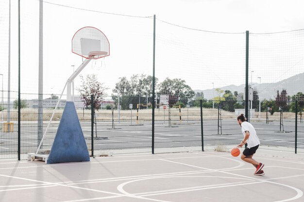 Hombre practicando baloncesto cerca de aro en la cancha al aire libre