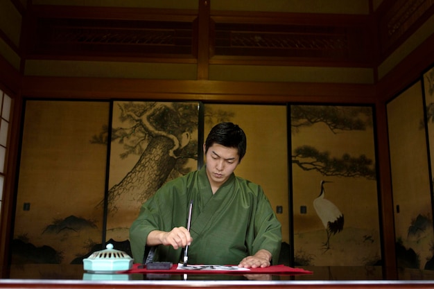 Foto gratuita hombre practicando la escritura japonesa con un pincel y tinta