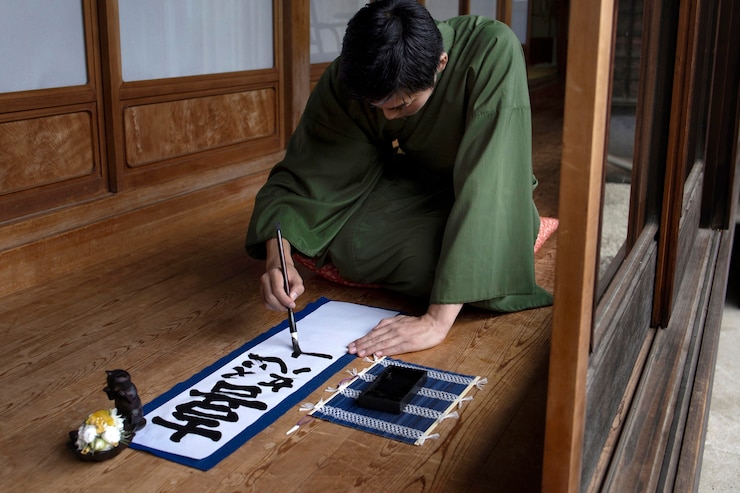 Foto gratuito hombre practicando la escritura japonesa con un pincel y tinta
