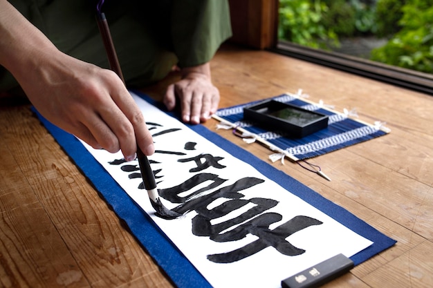 Foto gratuita hombre practicando la escritura japonesa con un pincel y tinta