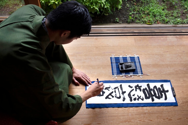 Foto gratuito hombre practicando la escritura japonesa con un pincel y tinta