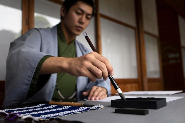 Foto gratuita hombre practicando la escritura japonesa con un pincel