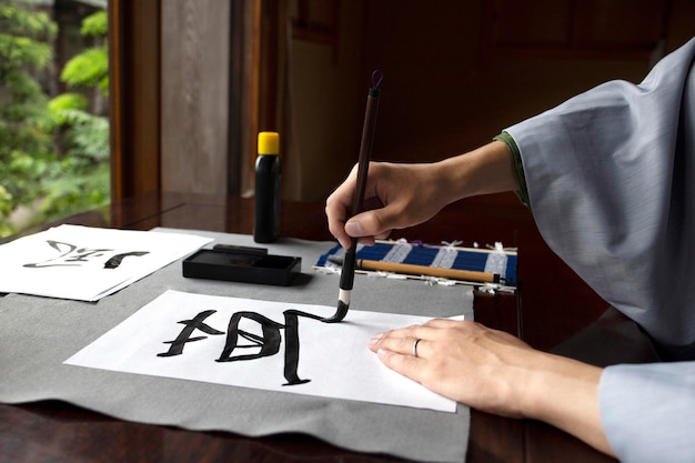 Hombre practicando la escritura japonesa con una variedad de herramientas