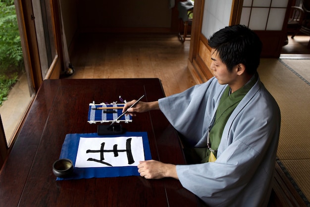 Hombre practicando la escritura japonesa con una variedad de herramientas