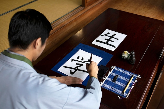 Hombre practicando la escritura japonesa con una variedad de herramientas