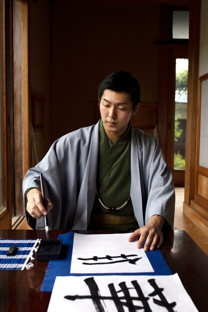 Hombre practicando la escritura japonesa con una variedad de herramientas