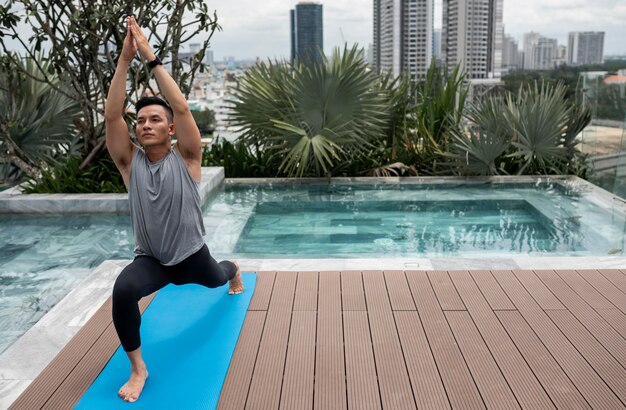 Hombre practicando yoga al aire libre con espacio de copia