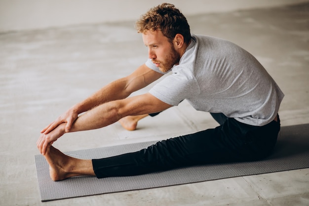 Hombre practicando yoga en la colchoneta en casa