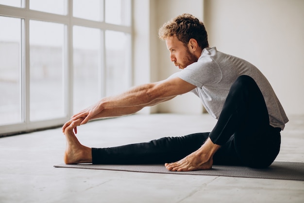 Hombre practicando yoga en la colchoneta en casa