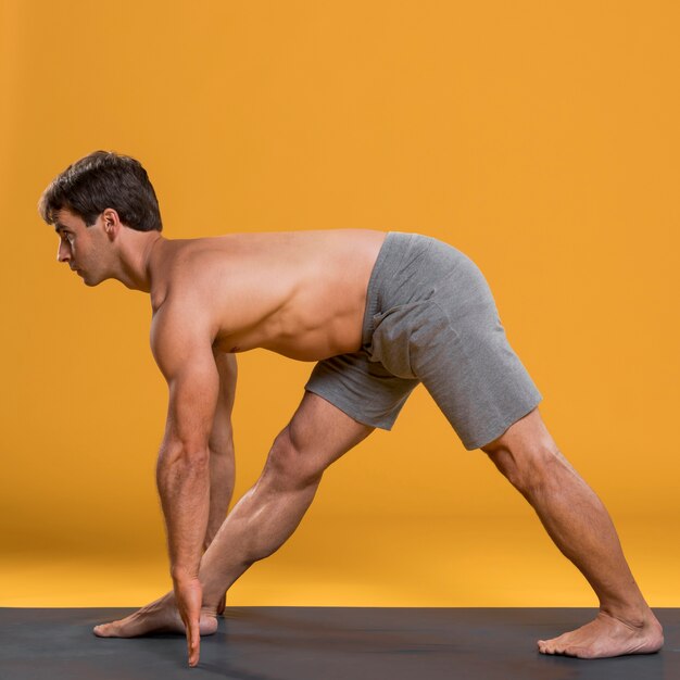 Hombre practicando yoga en colchoneta