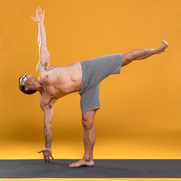 Hombre practicando yoga en colchoneta
