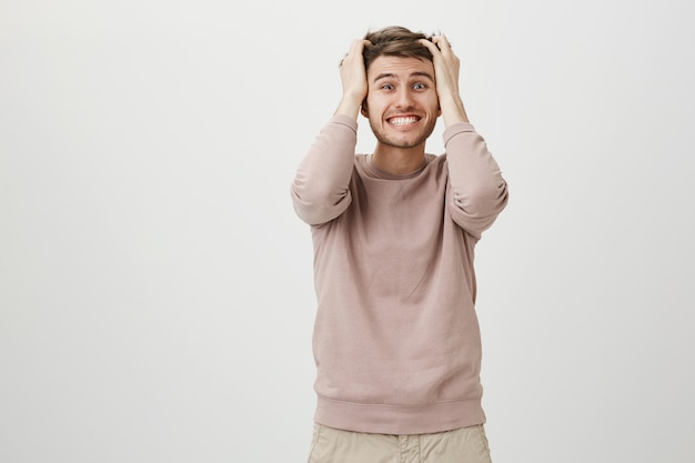 Hombre preocupado alarmado sacudiendo el pelo y apretando los dientes en pánico