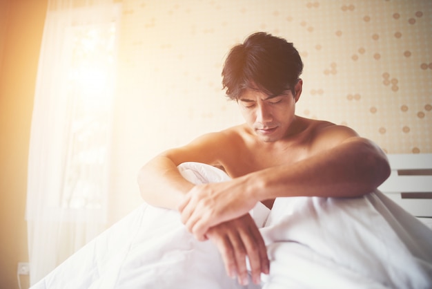 Foto gratuita hombre preocupado sentado en la cama por la mañana, pensando en algo serio