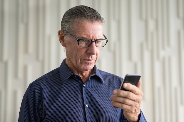 Hombre preocupante de lectura mayor de mensaje de texto en el teléfono