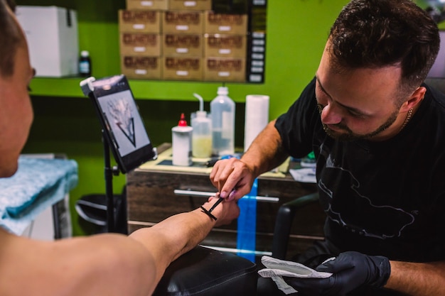 Hombre preparando el brazo del cliente para el tatuaje