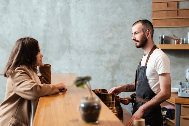 Hombre preparando café y hablando con mujer