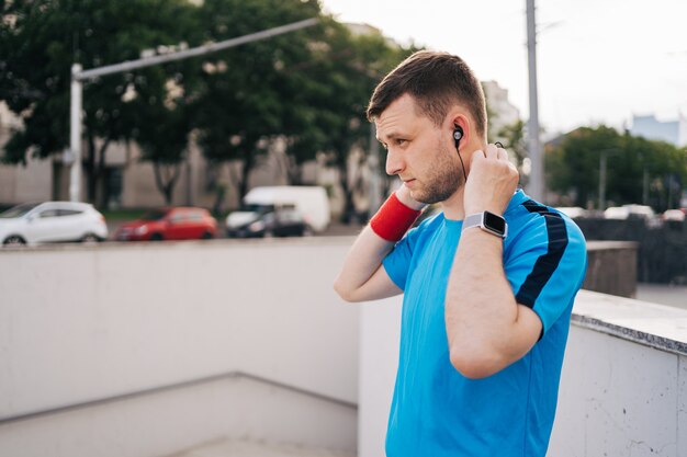 Hombre preparándose entrenamiento de la ciudad arreglando auriculares