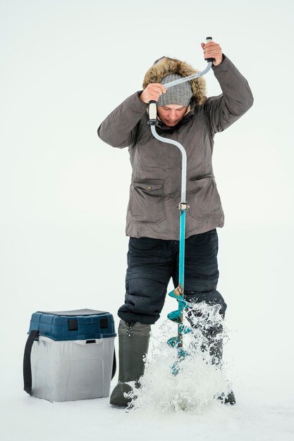 Hombre preparándose para pescar en el lago congelado