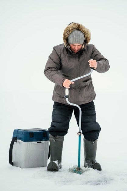 Hombre preparándose para pescar en el lago congelado