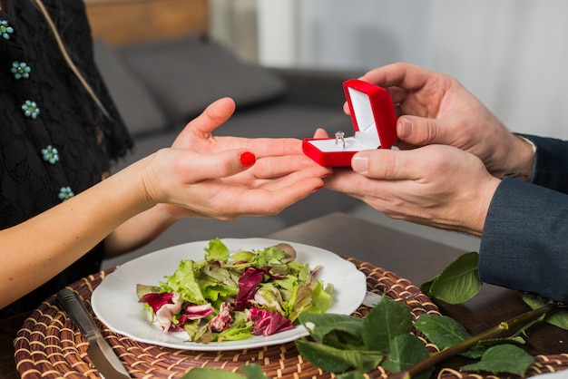 Foto gratuita hombre presentando caja de regalo con anillo a mujer en mesa con plato