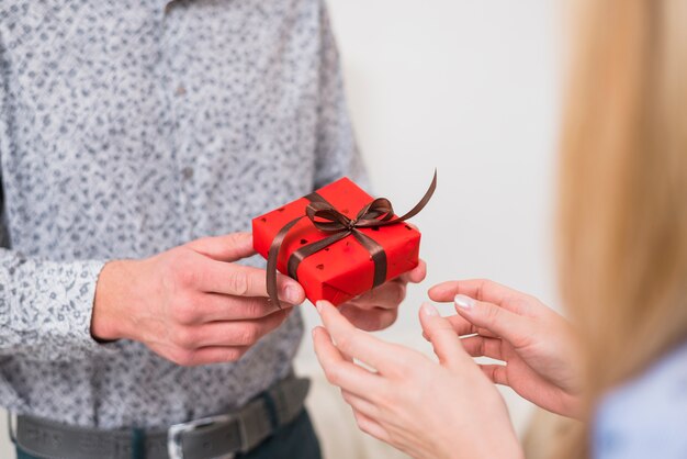 Hombre presentando una pequeña caja de regalo para mujer.