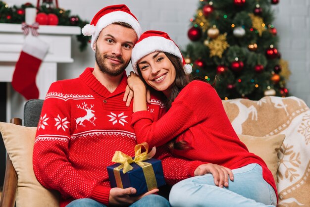 Hombre con presente sentado cerca de mujer feliz