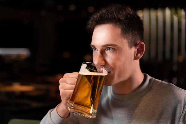 Hombre de primer plano bebiendo cerveza de taza