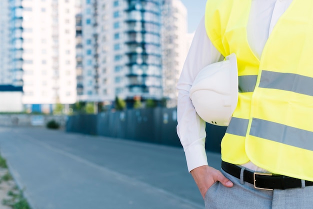 Hombre de primer plano con chaleco de seguridad con casco