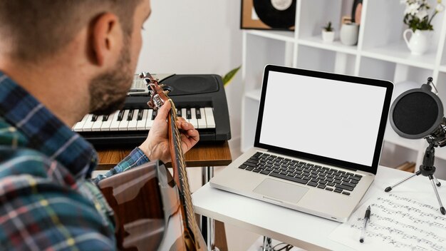 Hombre de primer plano grabando una canción con guitarra