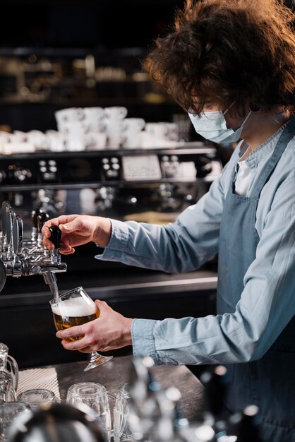 Hombre de primer plano con máscara vertiendo cerveza