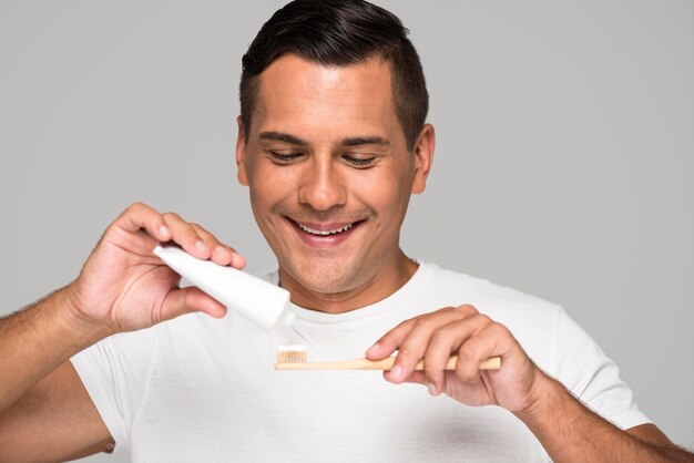 Hombre de primer plano poniendo pasta de dientes en el cepillo de dientes