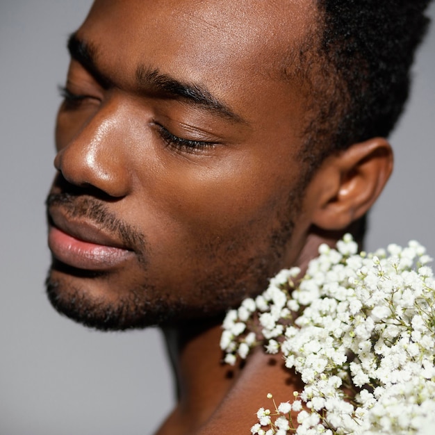 Hombre de primer plano posando con hermosas flores