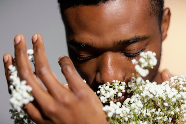 Hombre de primer plano que huele flores